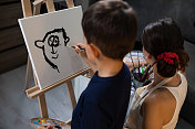 一个年轻的女人在帮一个男孩画画