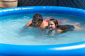 12岁的女孩和父亲在充气游泳池游泳