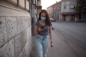 年轻女子戴着防护口罩在街上使用手机