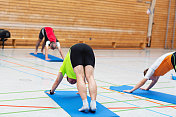 一群成年人在学校体育馆做瑜伽