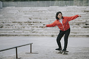 一个年轻的中国女孩周末在公共滑板公园练习滑板