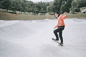一个年轻的中国女孩周末在公共滑板公园练习滑板
