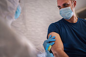 医生穿著防护服向病人手臂注射疫苗