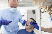 近距离拍摄专业牙医戴着防护口罩为病人做检查
