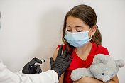 小儿科医生为可爱的女学生接种疫苗