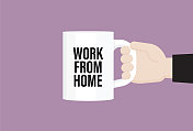商人拿着一个写着“在家工作”的咖啡杯