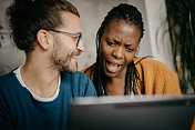年轻的混血夫妇在网上购物，并在数字平板电脑上聊天