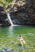 年轻女子在瀑布中游泳。土耳其穆格拉Koycegiz的极地瀑布。