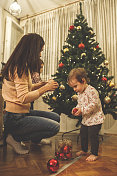 一个女人和她的两个小女儿在装饰圣诞树
