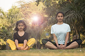 小女孩和少女做瑜伽在公园股票照片