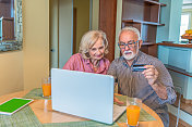 一对老年夫妇在家里一起享受网上购物计划。