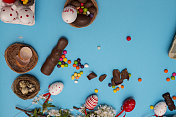 白色的木桌上放着复活节糖果。巧克力蛋，巧克力兔子和其他复活节糖果