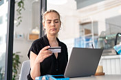 女人在咖啡馆用笔记本电脑，用信用卡在网上购物