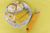 眼睛上有黄色玉米的鸡蛋，盘子里有黄色背景。