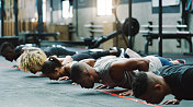 一群运动的年轻人在健身房做俯卧撑