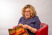 成熟的女人在自己织的丝绸上缝边。
