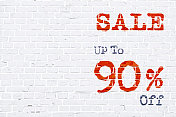 白色的砖墙制作了一个质朴的水平海报，上面有红色的油漆在砖上，上面写着“出售，高达九折”。向量背景复制空间到消息的左侧高达90% Off