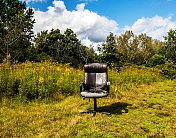 荒废的黑色办公椅被遗弃在草地上