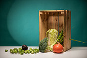新鲜的蔬菜和木篮放在绿色背景的桌子上