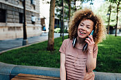 一个漂亮的红发女孩在街上讲电话的肖像