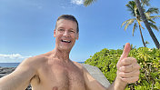 在夏威夷的海滩上，老男人竖起大拇指