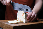 人手正在切一片松软的奶酪