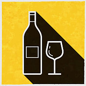 酒瓶和酒杯。图标与长阴影的纹理黄色背景