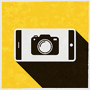 智能手机和相机。图标与长阴影的纹理黄色背景