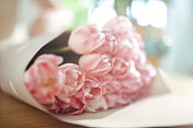 木桌上放着一束漂亮的粉红色郁金香。