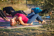 瑜伽教练和年轻女性一起上课，向后弯腰，用手肘支撑