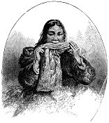 因纽特妇女咀嚼动物皮，因为她做了一双Mukluks/Kamiit - 19世纪