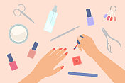 指甲护理概念。修剪女性的手和在指甲上涂指甲油。桌上的美甲设备