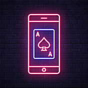 带扑克牌的智能手机。在砖墙背景上发光的霓虹灯图标