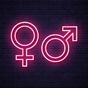性别符号。在砖墙背景上发光的霓虹灯图标