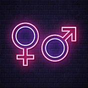 性别符号。在砖墙背景上发光的霓虹灯图标