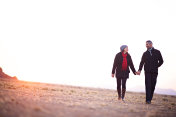 在沙漠中，日出时牵手散步的夫妇