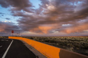 日落时分，一道护栏将公路与沙漠灌木隔开。