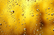 冰冷的玻璃覆盖着水滴凝结冷饮水滴金色的黄色-橙色的饮料背景雨点纹理近