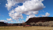 在维珍河谷的积云和太阳在红色谷仓与剪影的台地在犹他州洛克维尔