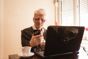 一个孤独的老人喝着早上的咖啡，用着手机