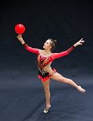 年轻的艺术体操运动员在手指上平衡球