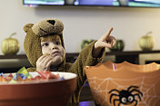 可爱的小男孩在熊的服装里吃或抓糖果