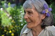 在花园里带着花的微笑的老妇人