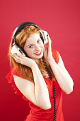 美丽快乐的红发年轻女子戴着耳机