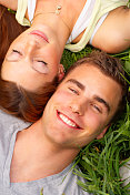 一对年轻夫妇躺在草地上