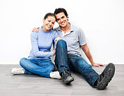 一对拥抱的夫妇坐在新家的地板上。