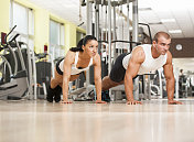 一对健身夫妇在健身房做俯卧撑