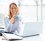 一个成熟的商业女性拿着笔记本电脑喝着咖啡的肖像