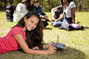 科技:拉丁少女数字平板电脑。朋友的背景。公园