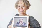 一名高级女性手持平板电脑，上面放着她的照片